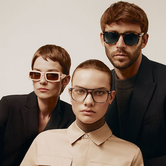 Tre modelli indossano occhiali da sole e da vista Persol in uno stile elegante e minimale; montature squadrate e tonde in acetato, tonalità neutre, atmosfera fashion e moderna.