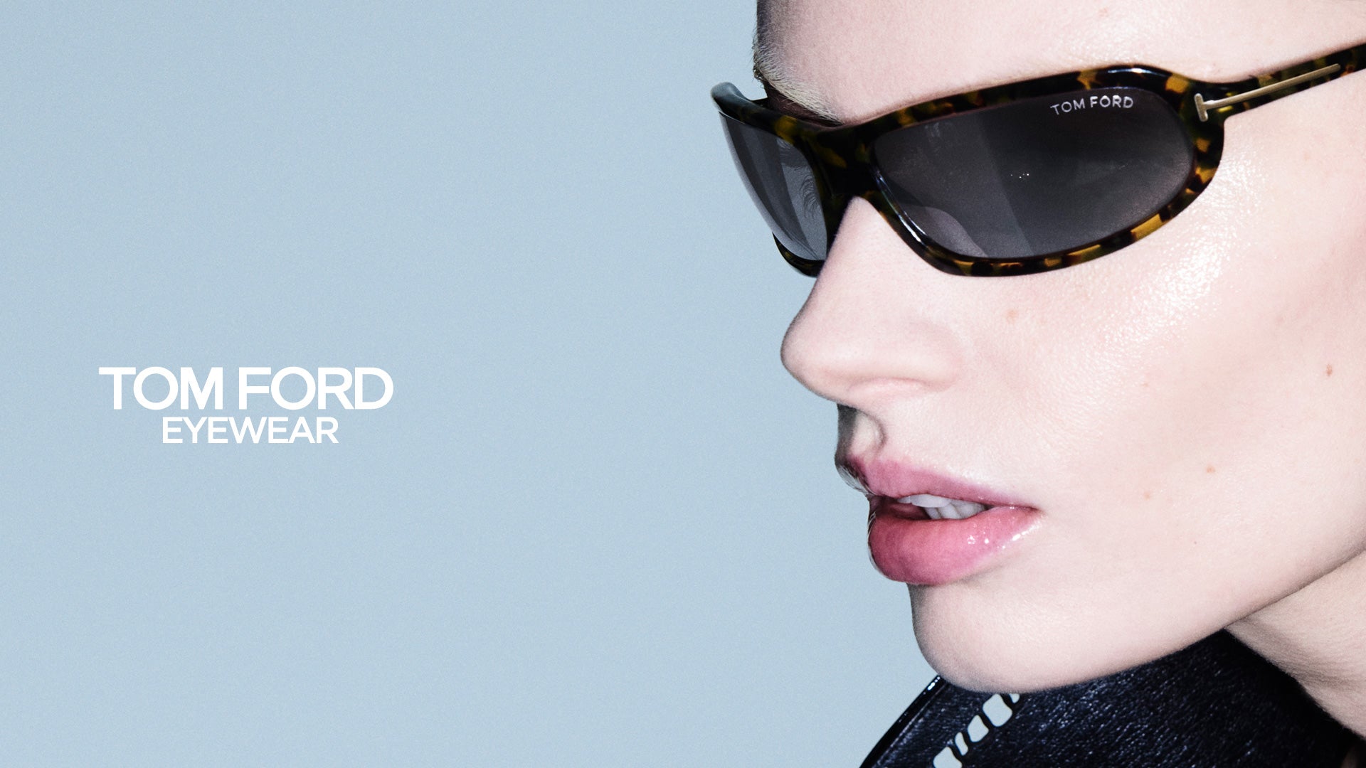 Primo piano di una modella che indossa occhiali da sole Tom Ford FT1400 tartarugati con lenti scure e logo Tom Ford Eyewear su sfondo azzurro - giarre.com